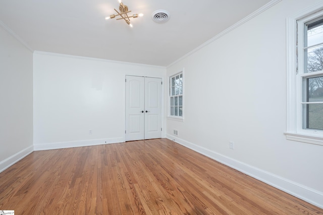 unfurnished bedroom with ornamental molding, visible vents, baseboards, and wood finished floors