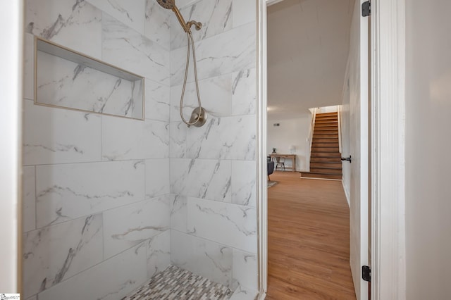 full bathroom featuring a tile shower and wood finished floors