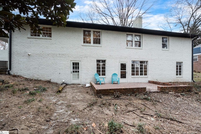 back of property with a patio area, brick siding, and a chimney