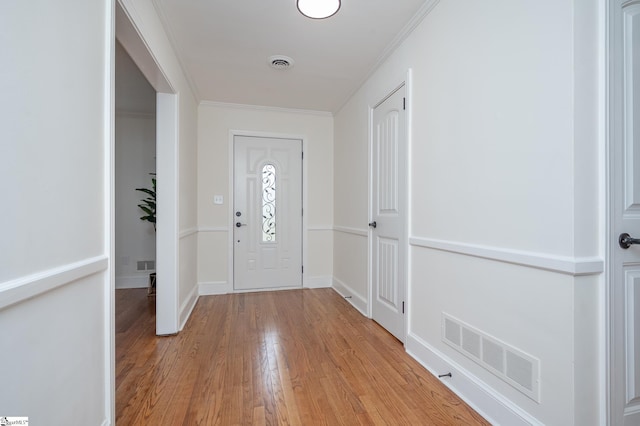 entryway featuring baseboards, visible vents, crown molding, and light wood finished floors