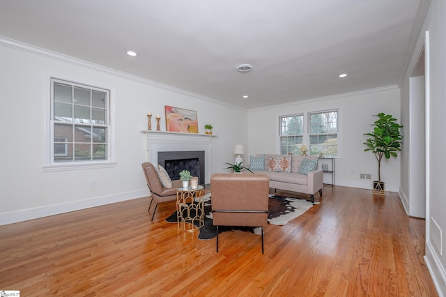 living room featuring a fireplace, visible vents, baseboards, light wood-style floors, and crown molding