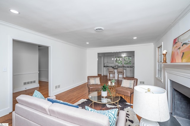 living area featuring a fireplace, visible vents, and crown molding