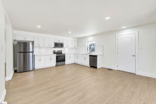 kitchen with stainless steel appliances, light wood finished floors, light countertops, and white cabinetry