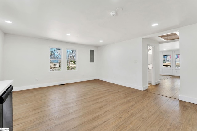 unfurnished living room featuring recessed lighting, baseboards, electric panel, light wood finished floors, and attic access