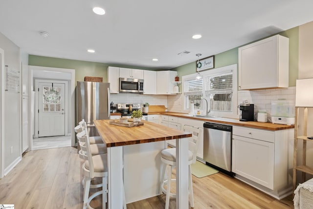 kitchen featuring wooden counters, a sink, white cabinetry, and stainless steel appliances