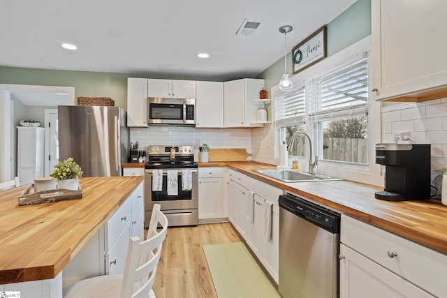 kitchen with butcher block counters, a sink, visible vents, white cabinetry, and appliances with stainless steel finishes