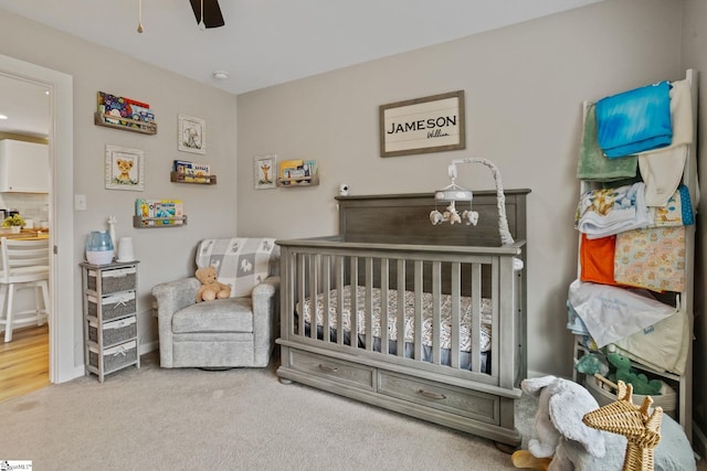 bedroom with a nursery area, ceiling fan, and carpet