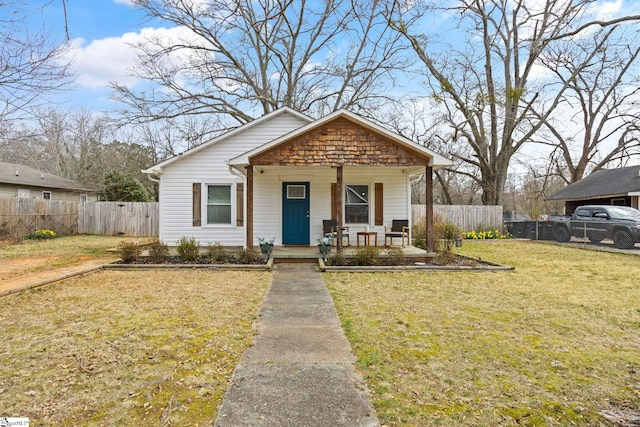 bungalow featuring covered porch, a front lawn, and fence