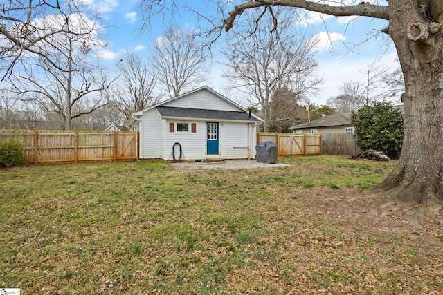 rear view of house with a gate, a fenced backyard, and a yard