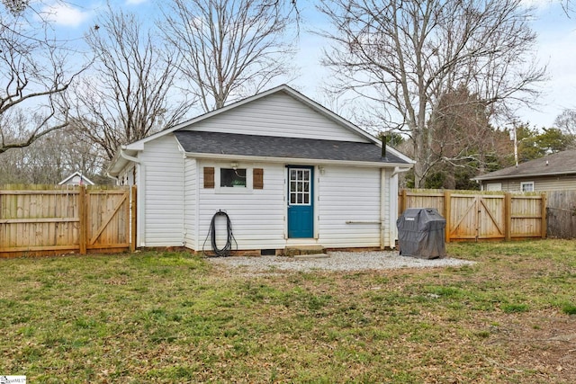 rear view of house featuring entry steps, a fenced backyard, a yard, and roof with shingles