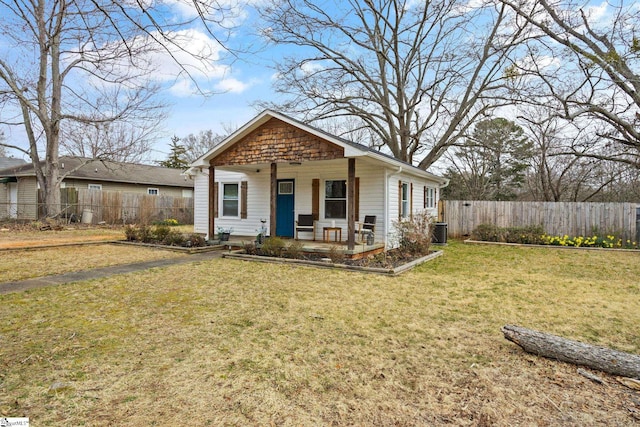 view of front of house featuring covered porch, a front lawn, central AC unit, and fence