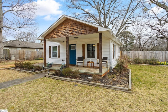 bungalow-style house with a front yard, covered porch, and fence