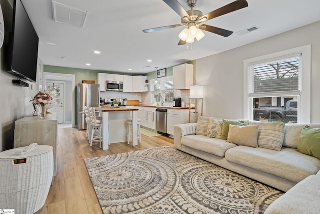 living room featuring light wood-style floors, recessed lighting, visible vents, and ceiling fan