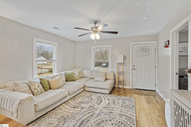 living area featuring a healthy amount of sunlight, visible vents, baseboards, and light wood finished floors