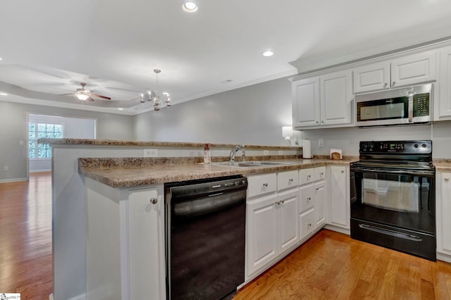 kitchen with a peninsula, a sink, black appliances, light wood finished floors, and crown molding