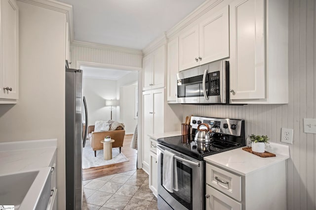 kitchen with light tile patterned floors, appliances with stainless steel finishes, white cabinetry, and light stone countertops