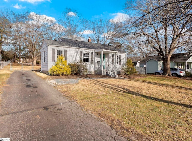 view of front of house with driveway, a chimney, fence, and a front yard