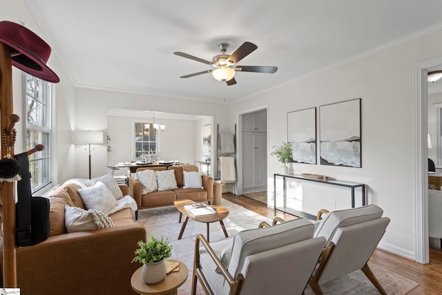 living room featuring crown molding, ceiling fan with notable chandelier, and light wood-style floors