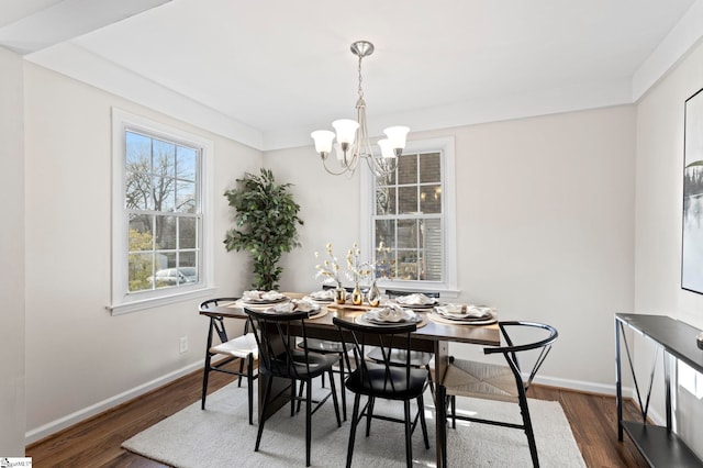 dining area featuring dark wood-type flooring, a chandelier, and baseboards