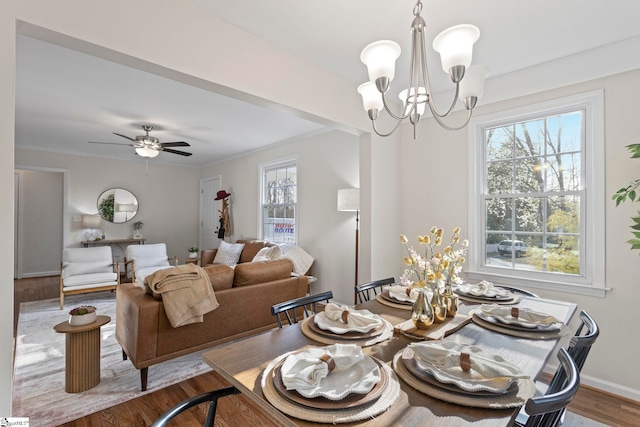 dining space featuring baseboards, ornamental molding, wood finished floors, and ceiling fan with notable chandelier