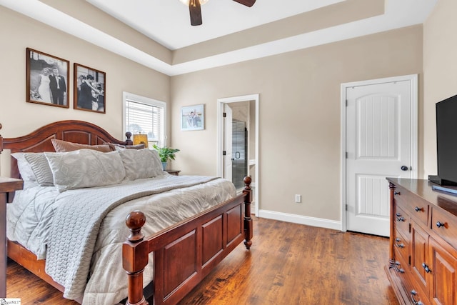 bedroom with ceiling fan, baseboards, a raised ceiling, and dark wood-style flooring