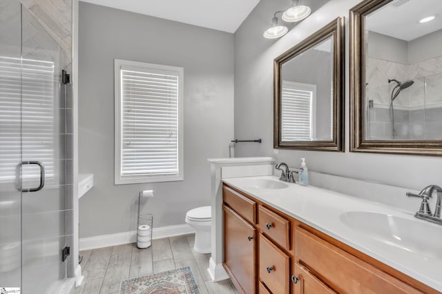 bathroom featuring a sink, a shower stall, baseboards, and double vanity