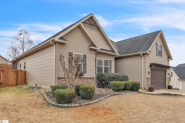 view of property exterior featuring a garage, stone siding, fence, and driveway