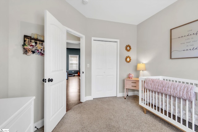 bedroom featuring a nursery area, a closet, carpet, and baseboards