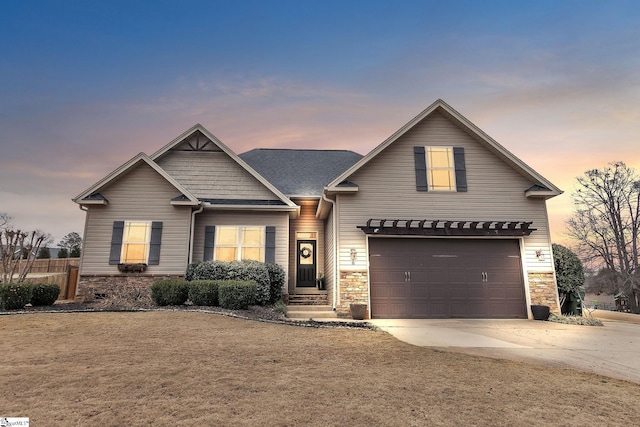 view of front of house with a garage, stone siding, and driveway