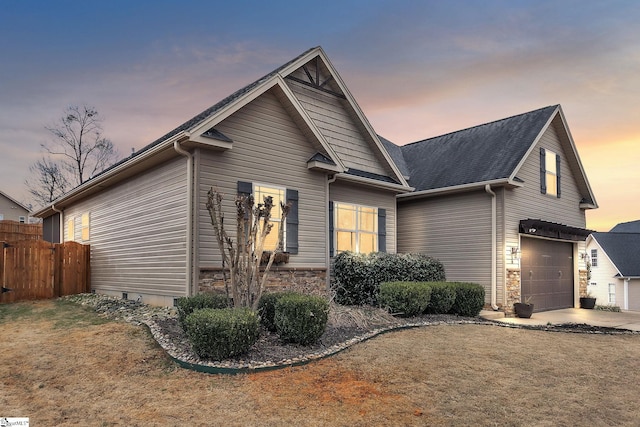 view of front of house with a garage, stone siding, fence, and driveway