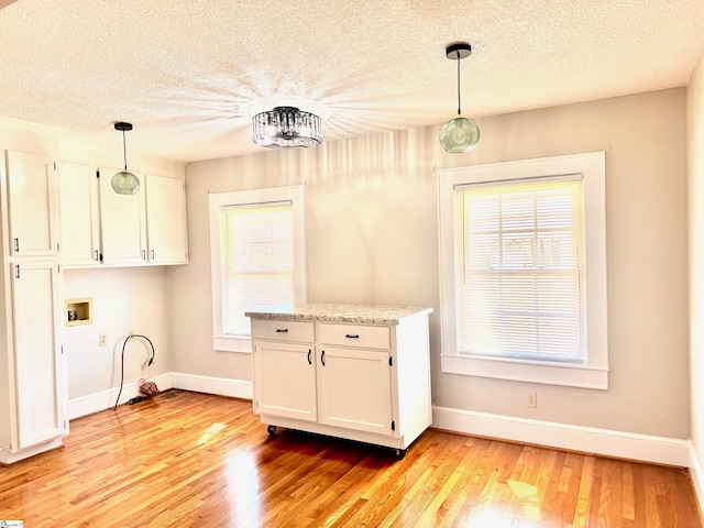 kitchen featuring a wealth of natural light, light wood-type flooring, pendant lighting, and white cabinetry