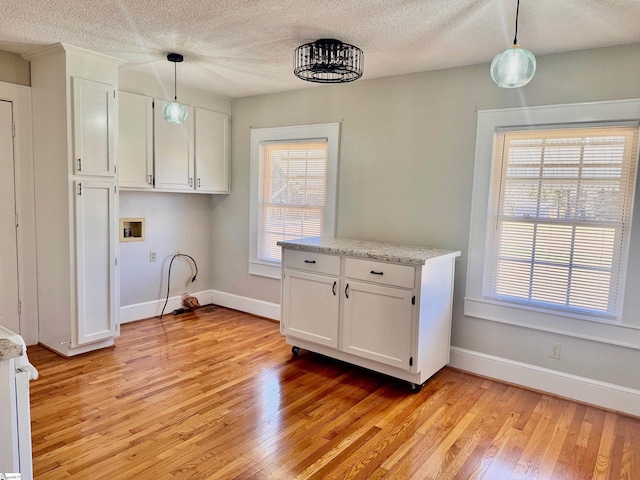 washroom with hookup for a washing machine, baseboards, light wood finished floors, and a textured ceiling