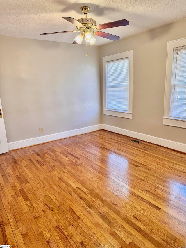 spare room with light wood-type flooring, visible vents, and a textured ceiling