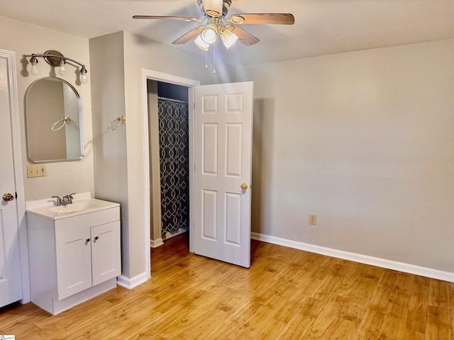 interior space with a ceiling fan, a sink, light wood-style flooring, and baseboards