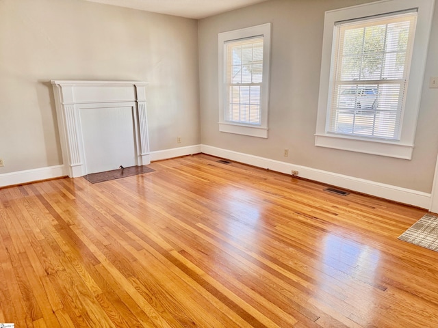 spare room with a healthy amount of sunlight, light wood-style flooring, and baseboards