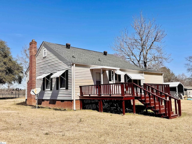 back of property with a deck, fence, roof with shingles, crawl space, and a lawn