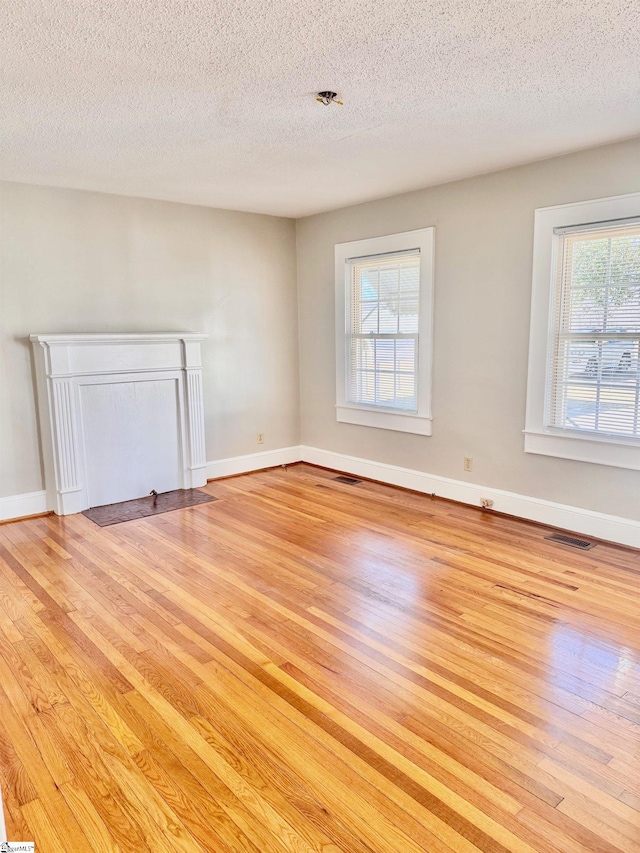 empty room with visible vents, light wood-style flooring, and baseboards