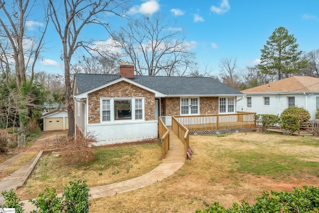 view of front facade with driveway, a chimney, an outbuilding, a wooden deck, and a front yard