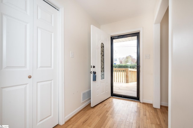 doorway to outside with light wood-type flooring, baseboards, and visible vents