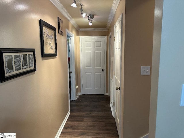 corridor with dark wood-style floors, track lighting, crown molding, and baseboards