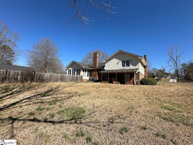 back of house with central AC unit, a chimney, fence, and a sunroom