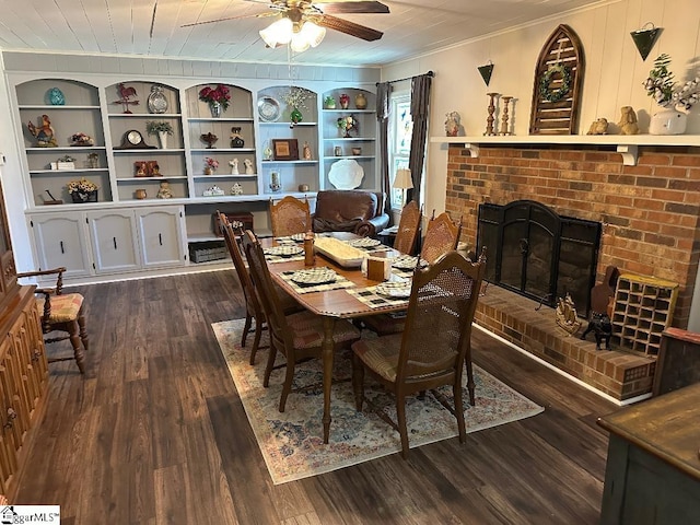 dining area featuring dark wood-type flooring, a fireplace, a ceiling fan, built in features, and crown molding