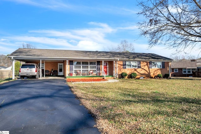 single story home with an attached carport, aphalt driveway, covered porch, brick siding, and a front lawn