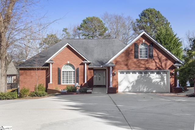 traditional home with driveway, roof with shingles, a garage, and brick siding