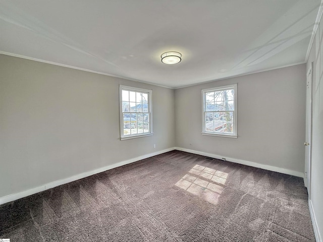 spare room with dark colored carpet, ornamental molding, and a wealth of natural light