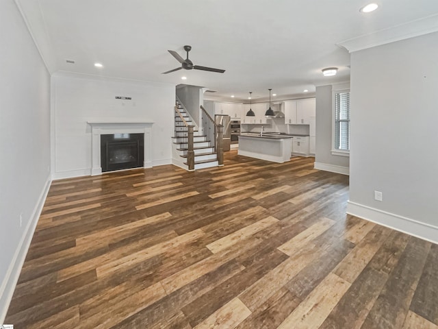 unfurnished living room featuring dark wood-style flooring, a fireplace, recessed lighting, stairway, and ornamental molding