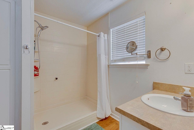 full bath featuring a sink, a shower stall, a textured ceiling, and wood finished floors