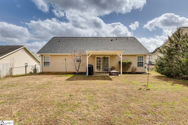 rear view of property with a patio area, a shingled roof, fence, and a lawn