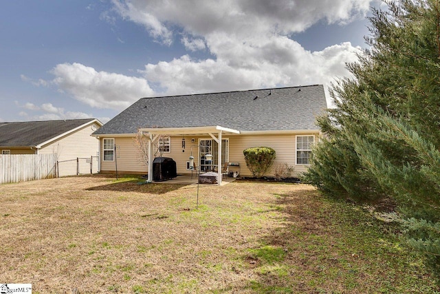 back of house featuring a patio area, fence, a lawn, and roof with shingles