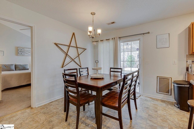 dining room with a chandelier, visible vents, and baseboards